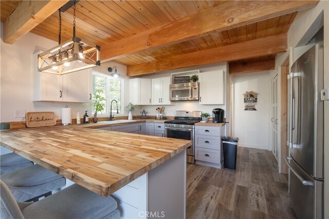 1154 Yukon Dr, Lake Arrowhead, CA 92352 - kitchen with stainless steel appliances, a sink, butcher block countertops, a chandelier, and a peninsula