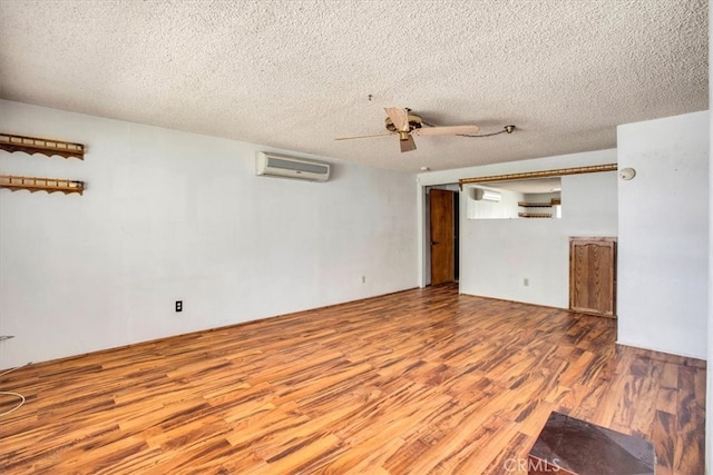 unfurnished living room featuring a wall mounted AC, a textured ceiling, hardwood / wood-style flooring, and ceiling fan