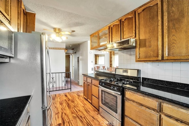 kitchen featuring tasteful backsplash, ceiling fan, appliances with stainless steel finishes, light hardwood / wood-style flooring, and a textured ceiling