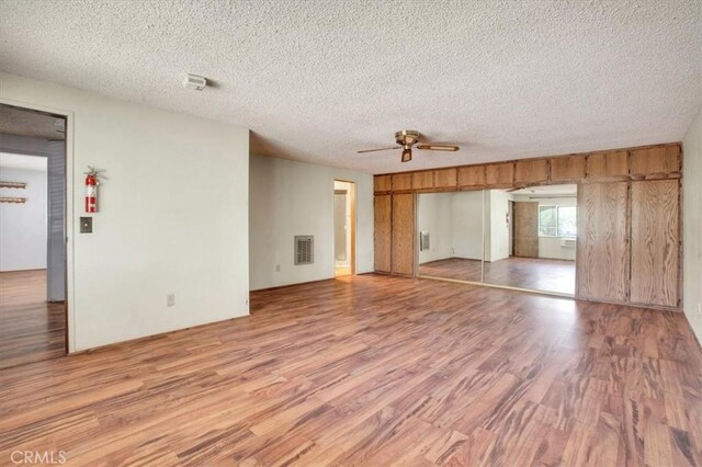 unfurnished room with a textured ceiling, ceiling fan, and light hardwood / wood-style floors