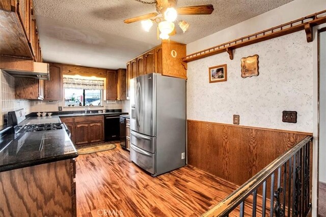 kitchen with ceiling fan, stainless steel refrigerator with ice dispenser, light wood-type flooring, stove, and a textured ceiling