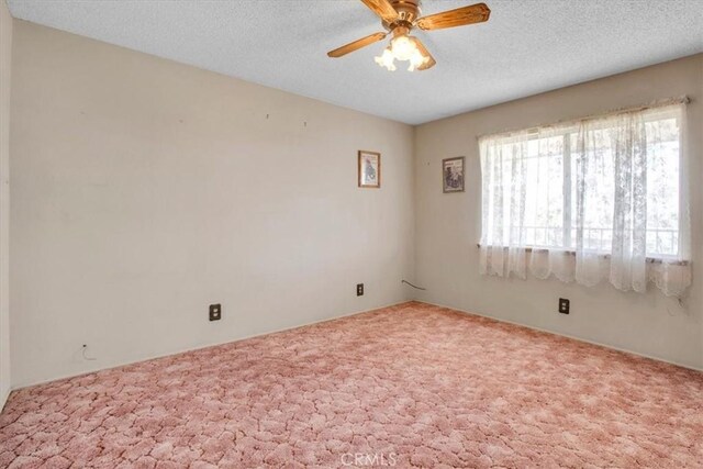 carpeted spare room with a textured ceiling and ceiling fan