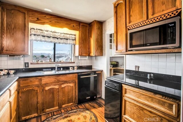 kitchen featuring sink, dishwasher, wood-type flooring, and decorative backsplash