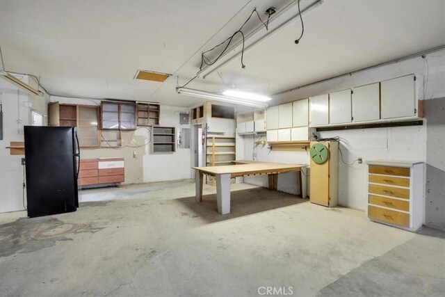 basement with a workshop area and black refrigerator