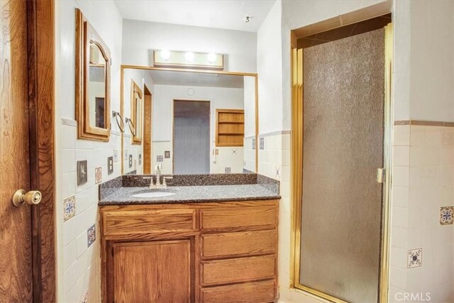 bathroom featuring tile walls, a shower with shower door, and vanity