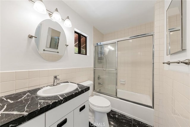 full bathroom with vanity, combined bath / shower with glass door, tile walls, and toilet