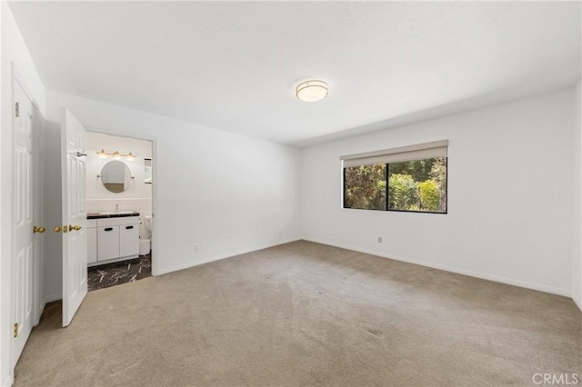 unfurnished bedroom with ensuite bathroom, light colored carpet, and sink