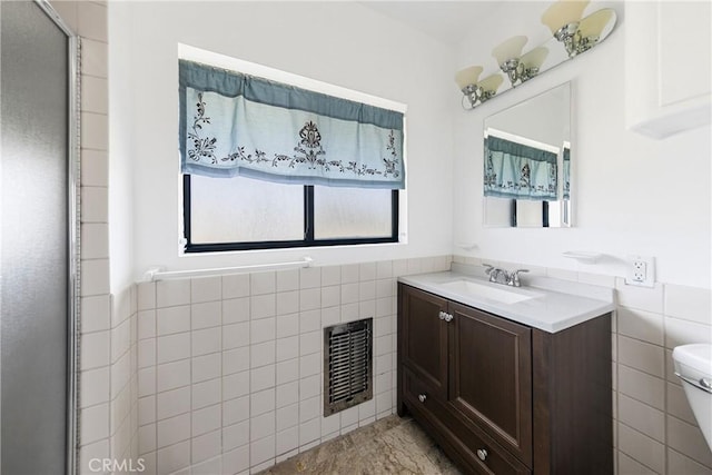 bathroom with vanity, toilet, tile walls, and heating unit