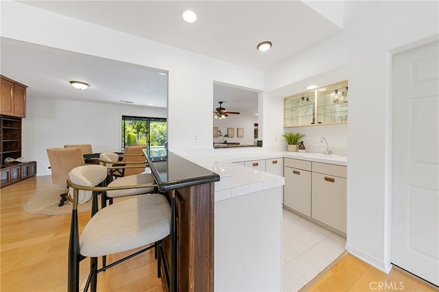 kitchen featuring white cabinets, sink, light hardwood / wood-style flooring, ceiling fan, and kitchen peninsula