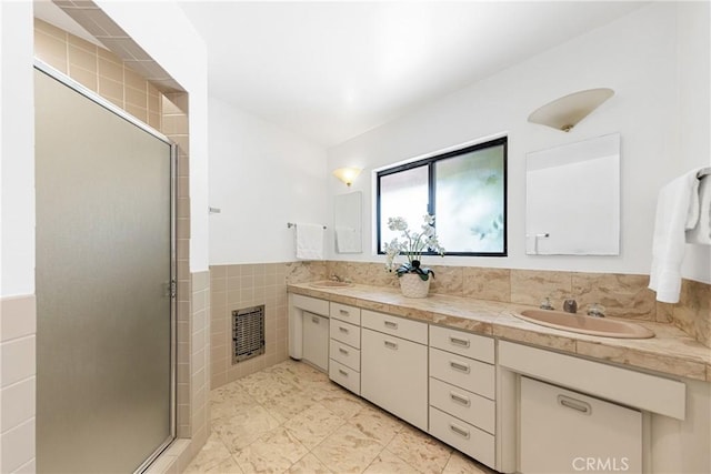 bathroom with a shower with door, vanity, and tile walls