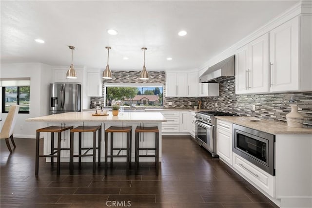 kitchen featuring pendant lighting, a center island, wall chimney range hood, a wealth of natural light, and appliances with stainless steel finishes