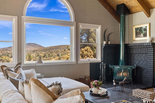 interior space featuring vaulted ceiling with beams, a wood stove, a mountain view, and plenty of natural light