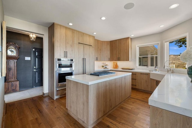 kitchen with light hardwood / wood-style flooring, stainless steel appliances, a center island, and sink