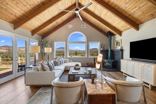 living room featuring high vaulted ceiling, a mountain view, a wood stove, ceiling fan, and hardwood / wood-style floors