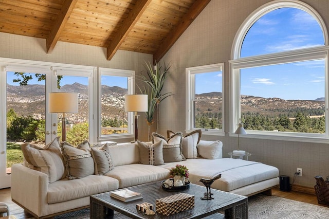 sunroom featuring lofted ceiling with beams, a mountain view, and a healthy amount of sunlight