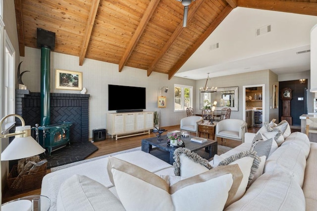 living room featuring wood ceiling, a chandelier, beamed ceiling, a wood stove, and hardwood / wood-style floors