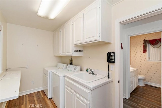 laundry room with dark wood-type flooring, cabinets, separate washer and dryer, and sink