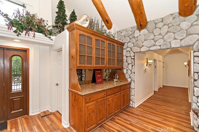 interior space featuring beamed ceiling, sink, light hardwood / wood-style floors, and light stone counters