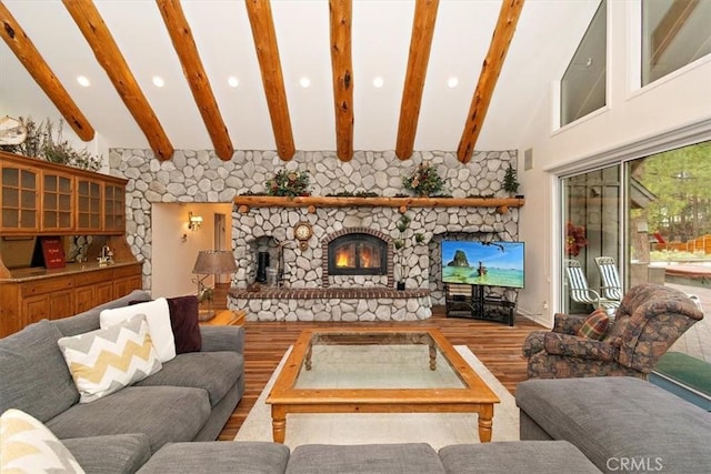 living room with hardwood / wood-style flooring, a stone fireplace, and beamed ceiling