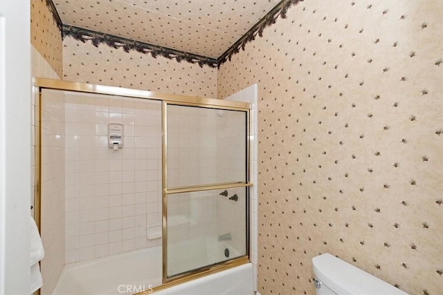 bathroom featuring bath / shower combo with glass door and toilet