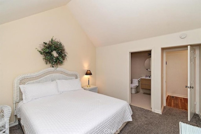 bedroom featuring ensuite bathroom, lofted ceiling, and carpet flooring