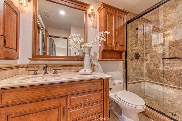 full bathroom with vanity, a shower stall, toilet, and visible vents