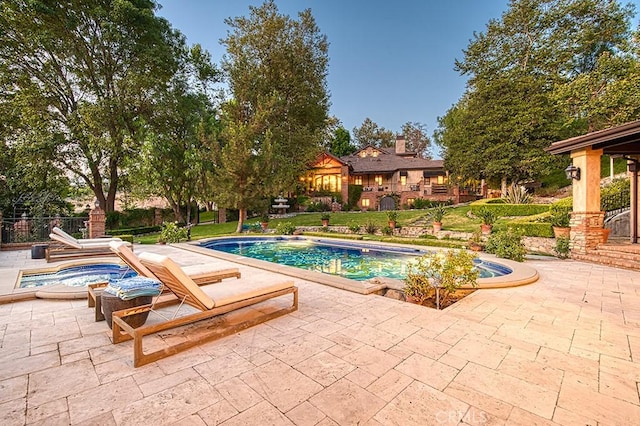 outdoor pool with a patio and a hot tub