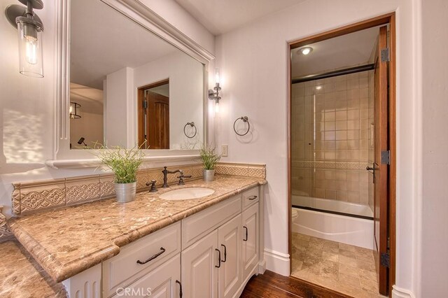 full bath with vanity, baseboards, and enclosed tub / shower combo