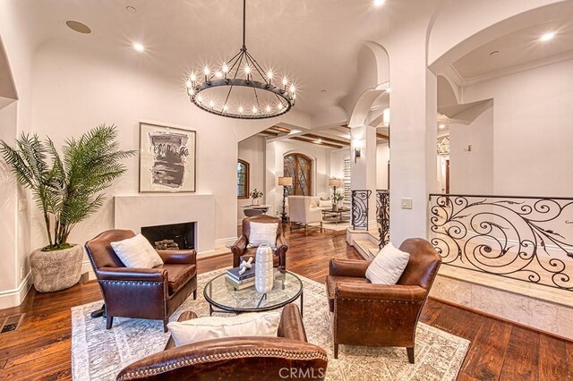 interior space featuring arched walkways, a fireplace, an inviting chandelier, and hardwood / wood-style floors