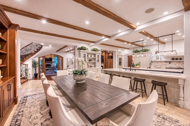 dining area featuring beamed ceiling and sink