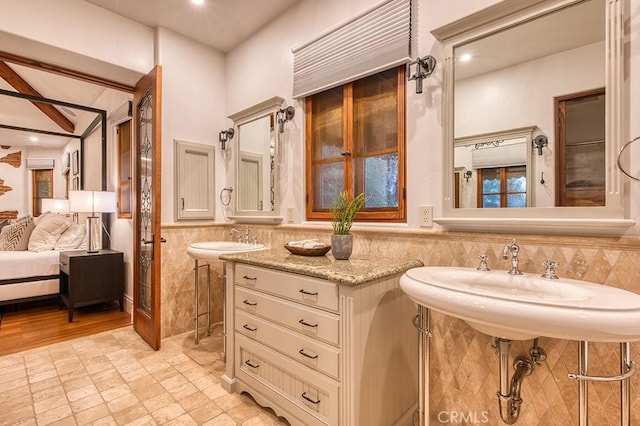 bathroom featuring beamed ceiling, sink, and tile walls