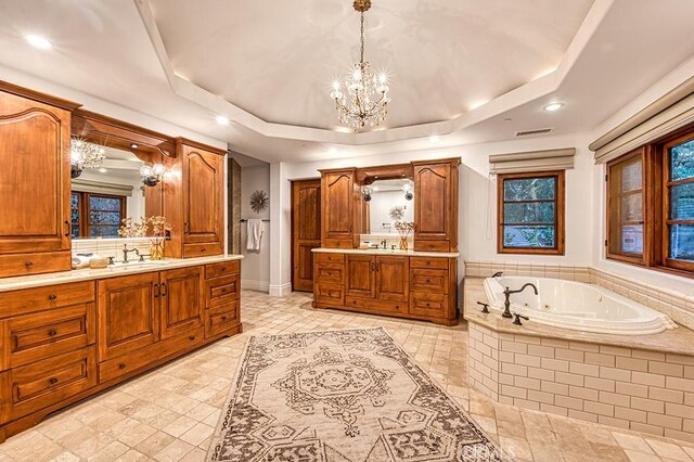 bathroom with visible vents, two vanities, a sink, a tub with jets, and a raised ceiling