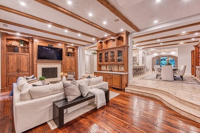 living room with sink, dark wood-type flooring, a fireplace, and beamed ceiling