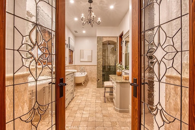 bathroom featuring tile walls, a tile shower, a bidet, vanity, and a notable chandelier