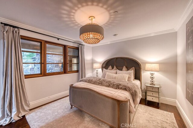 bedroom with baseboards, wood finished floors, and ornamental molding