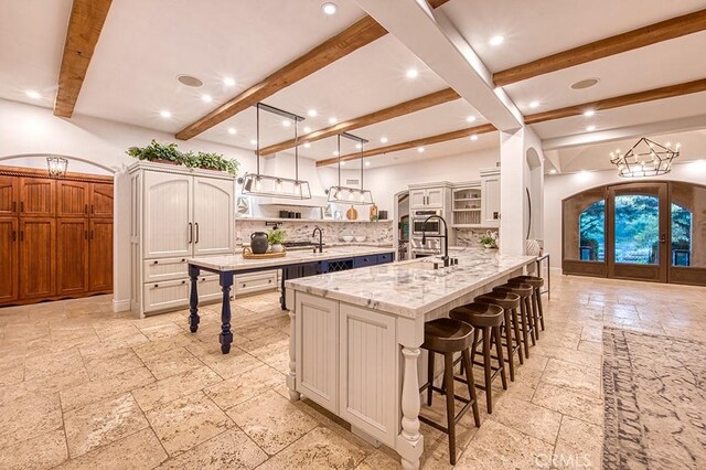 kitchen with stone tile floors, a breakfast bar, open shelves, arched walkways, and decorative backsplash