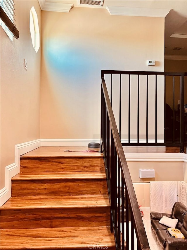 stairs featuring ornamental molding and hardwood / wood-style floors