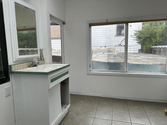 kitchen with light tile patterned flooring, plenty of natural light, white cabinets, and sink