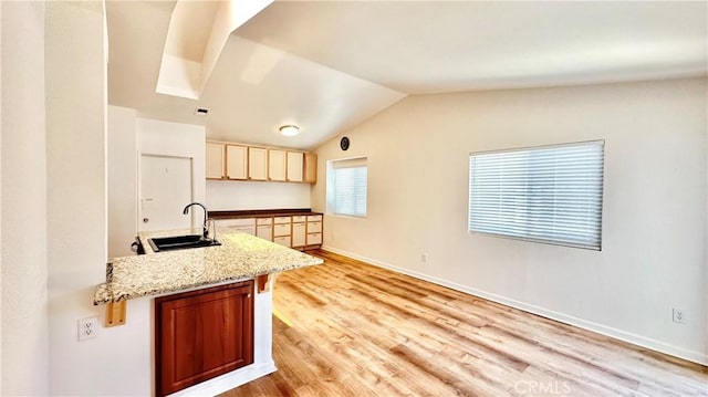 kitchen featuring sink, vaulted ceiling, cream cabinetry, and light wood-type flooring