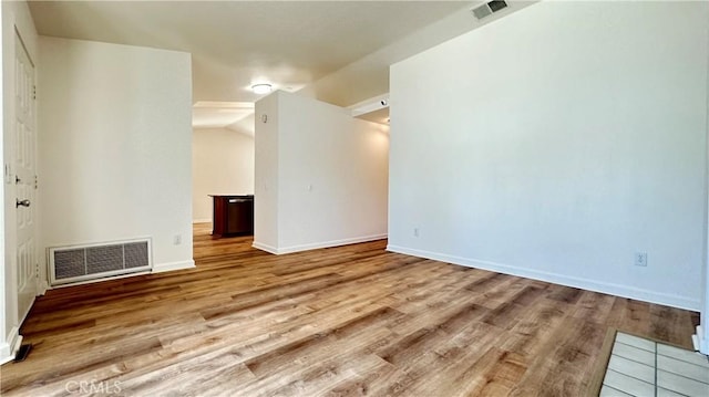 spare room featuring light wood-type flooring and vaulted ceiling