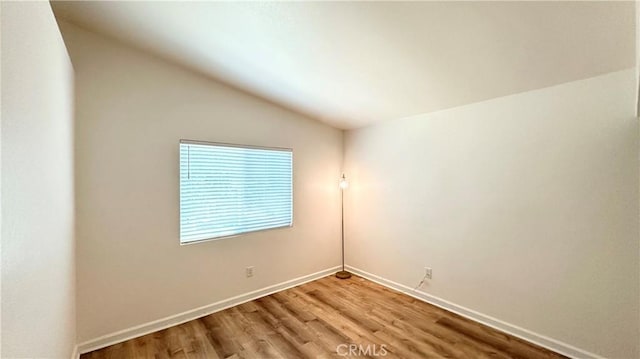 empty room featuring lofted ceiling and hardwood / wood-style floors