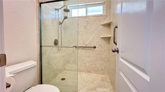 bathroom with a shower with shower door and toilet