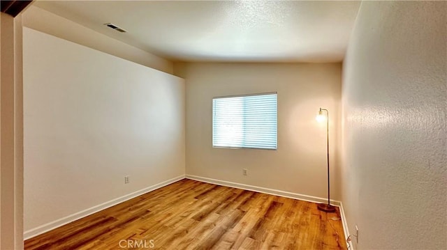 unfurnished room with lofted ceiling and light wood-type flooring