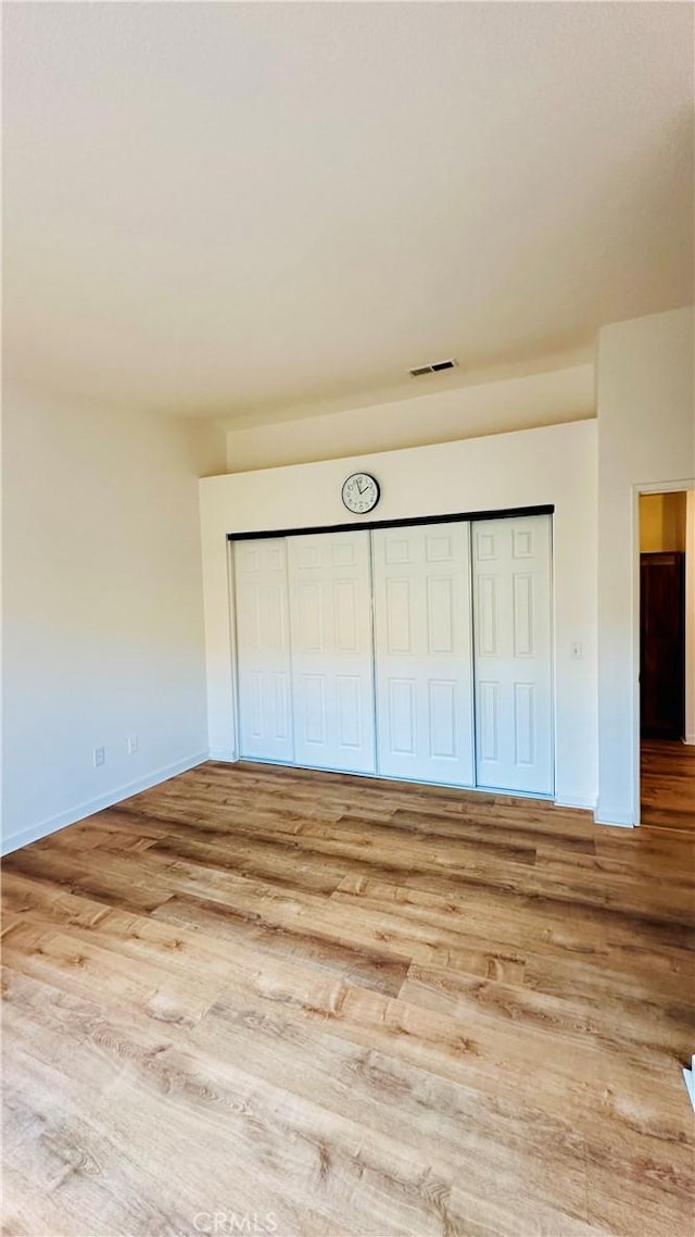 unfurnished bedroom with a closet and light hardwood / wood-style floors