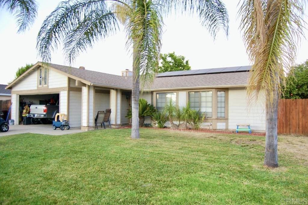 ranch-style house with solar panels, a garage, and a front lawn