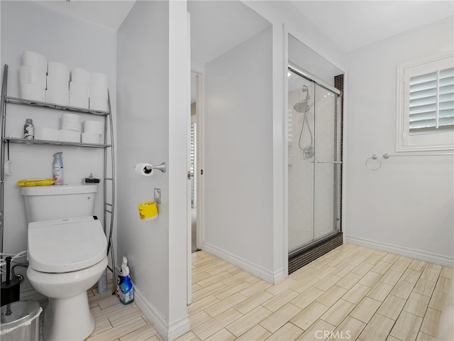 bathroom featuring a shower with door and toilet