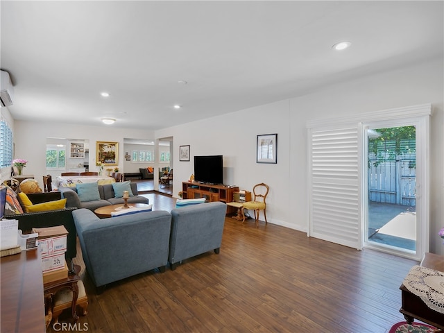 living room with a wall mounted air conditioner and dark hardwood / wood-style flooring