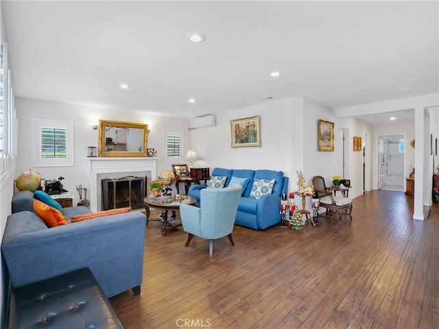 living room featuring an AC wall unit, a high end fireplace, and hardwood / wood-style flooring