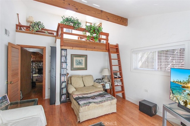 living area with beam ceiling, visible vents, and wood finished floors
