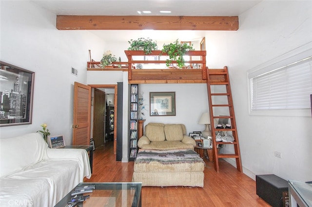 living area with beam ceiling and wood finished floors